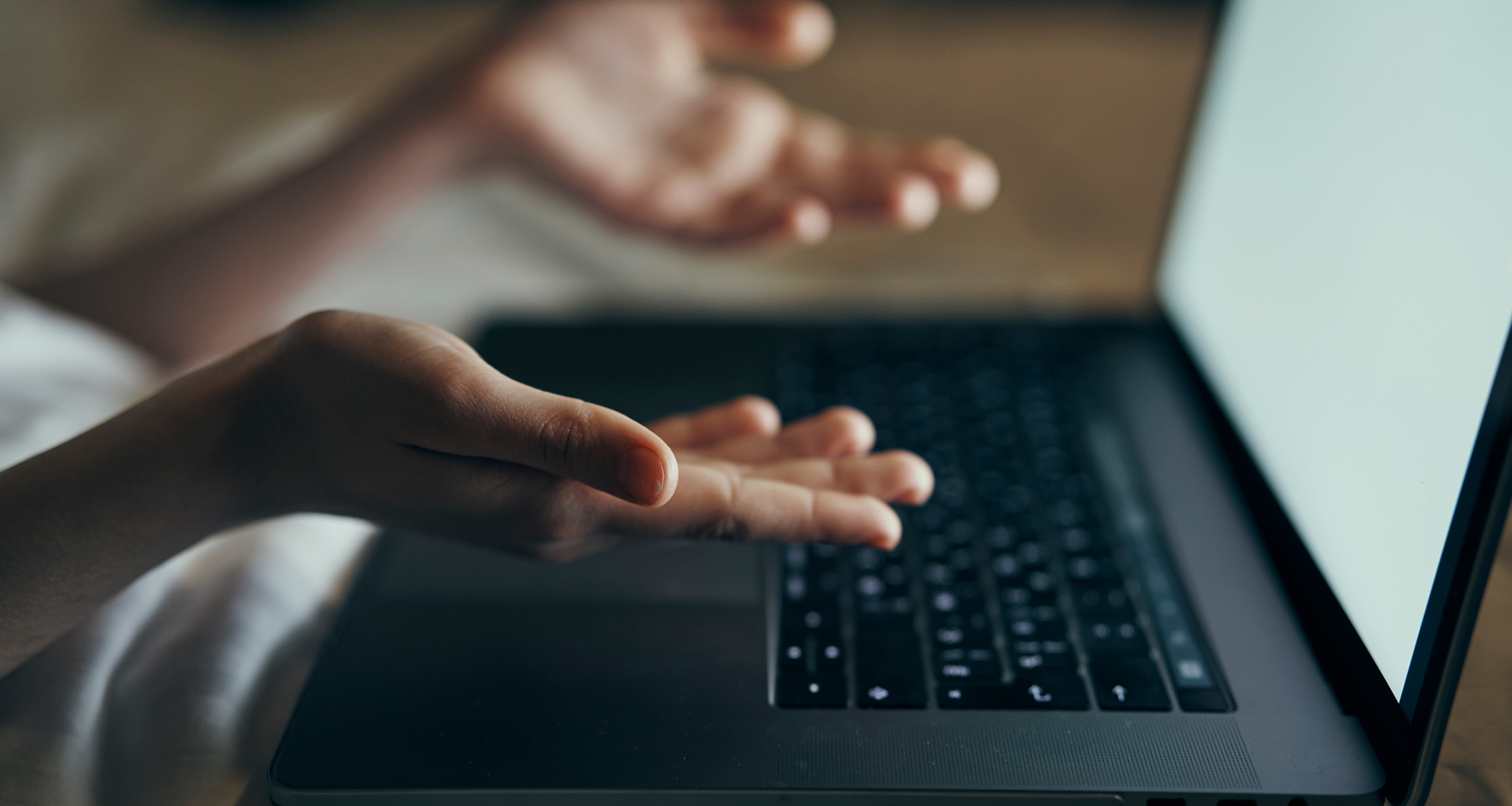 gesturing at laptop in bed-internal image